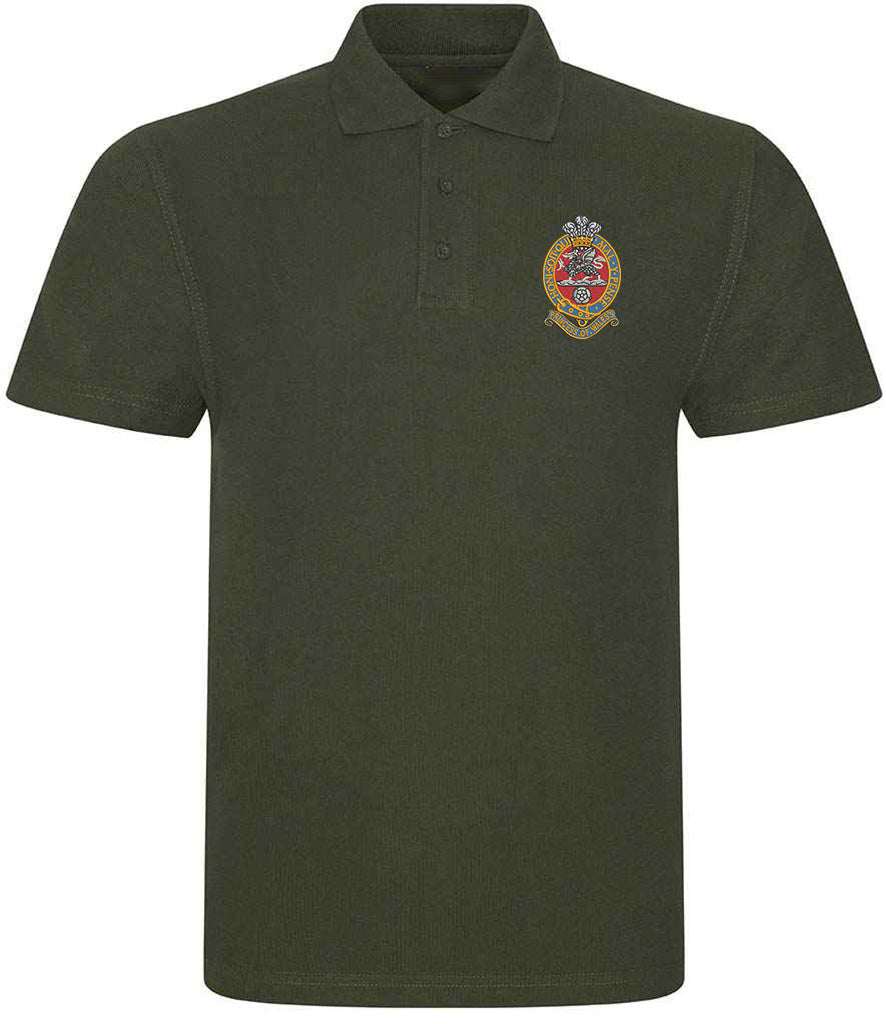 Green Queens Regiment polo shirt with embroidered emblem, ribbed collar, and three-button placket, made from 50% polyester and 50% cotton.